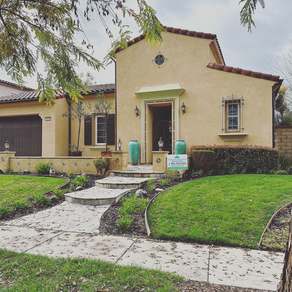 Completed tile roof replacement on a Mediterranean-style home, with American Highland Roofing yard sign