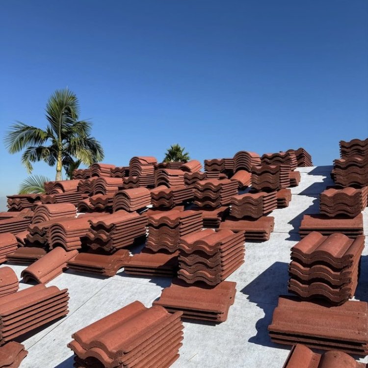 Clay roof tiles stacked and sorted across a rooftop during a tile lift and relay project